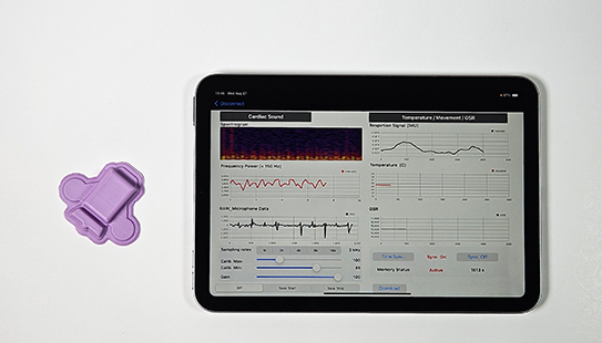 The wearable polygraph next to a tablet, showing real-time physiologic data captured and streamed from the device.